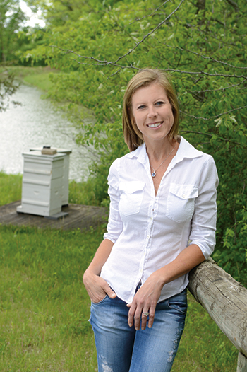 Sharon Krause pauses to enjoy the natural beauty surrounding her hives, which are set close to a pond so her busy workers can easily find essential water.