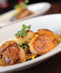 Robust poblano whipped potatoes, bacon-sauteed kale, and a cherry tomato and olive oil-based sauce provide refined touches to the tender scallops.